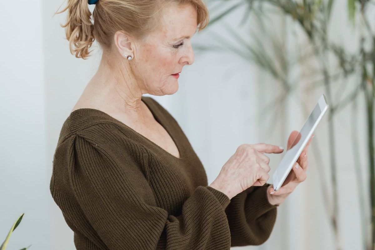 Thoughtful woman over 50 using a tablet in a bright living room