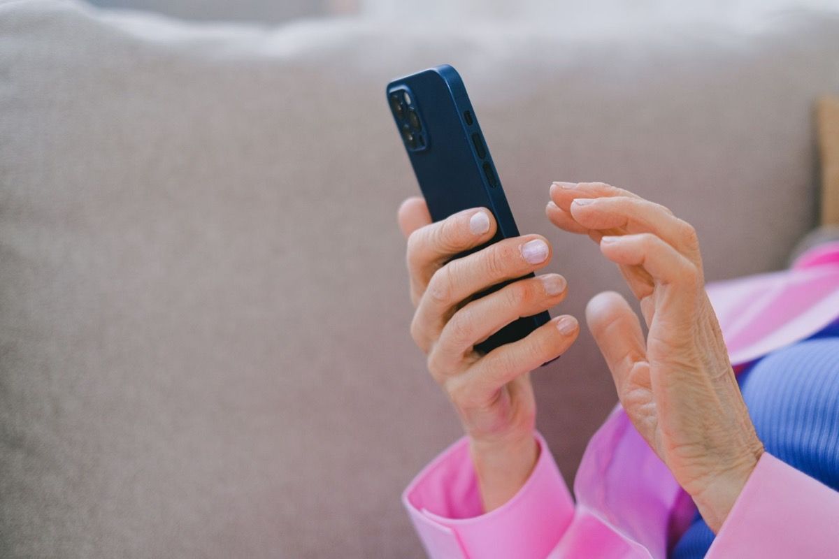Adult over 50 holding a smartphone while thinking through what to share in an online dating profile