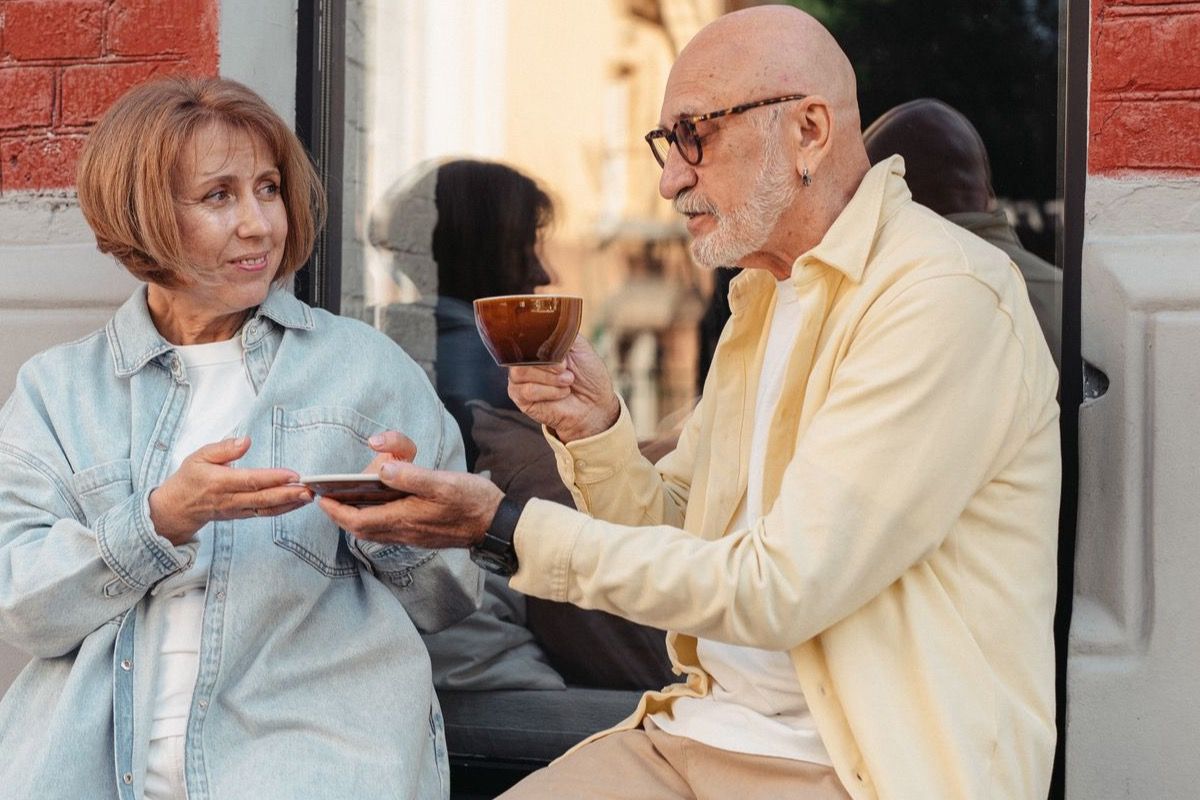 Man and woman over 50 sharing coffee and conversation outside a cafe