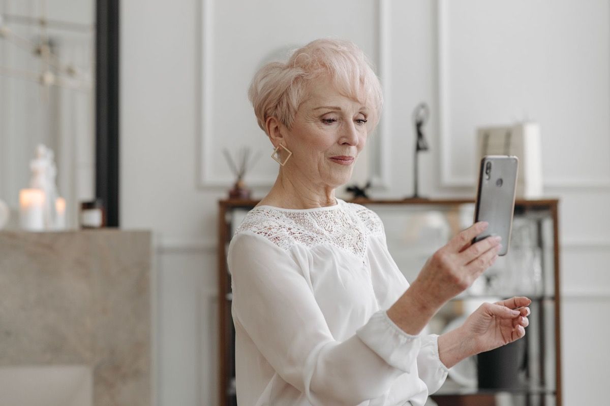 Elegant woman over 60 confidently using her smartphone in a modern living room