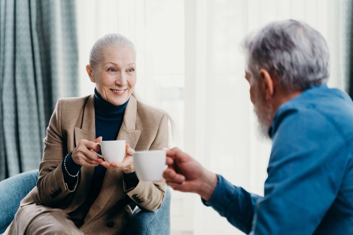 Two adults over 50 talking over coffee indoors